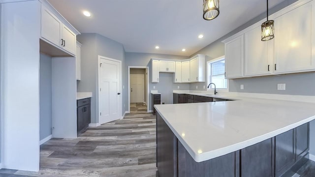 kitchen with pendant lighting, sink, kitchen peninsula, and white cabinets