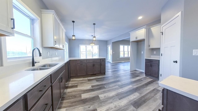 kitchen with hanging light fixtures, white cabinetry, sink, and dark hardwood / wood-style flooring