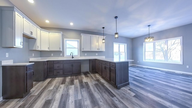 kitchen featuring sink, white cabinetry, dark hardwood / wood-style flooring, decorative light fixtures, and kitchen peninsula