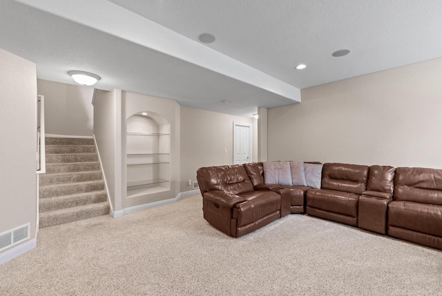 living room with light carpet, built in shelves, and a textured ceiling