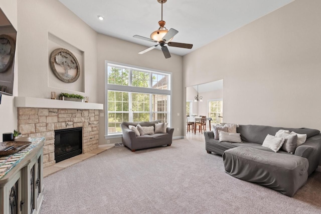 living room with a high ceiling, ceiling fan, carpet, and a fireplace