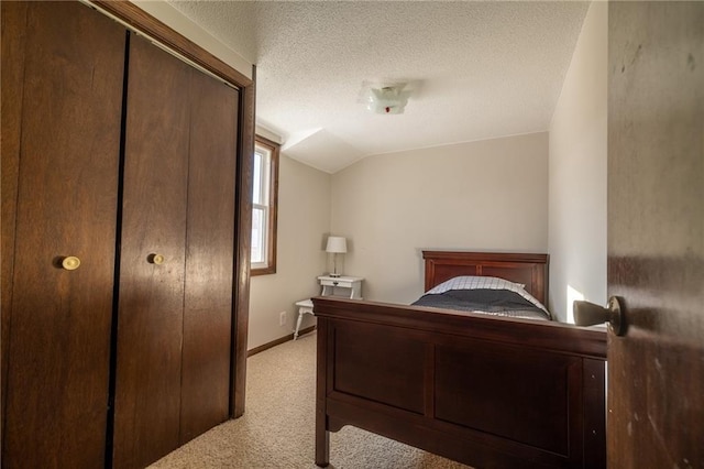 bedroom with lofted ceiling, light carpet, a textured ceiling, and a closet