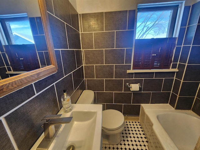 bathroom featuring a washtub, tile walls, and toilet