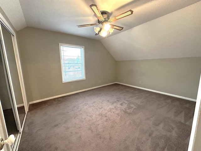 bonus room with ceiling fan, lofted ceiling, dark carpet, and a textured ceiling