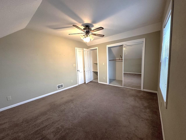 unfurnished bedroom featuring ceiling fan, vaulted ceiling, and dark colored carpet