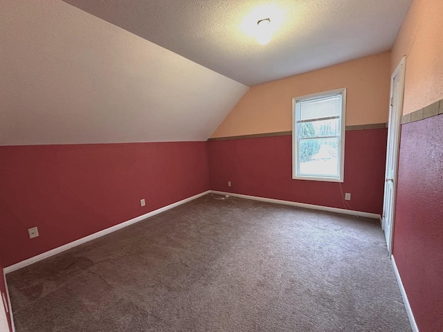 bonus room featuring vaulted ceiling, a textured ceiling, and carpet flooring