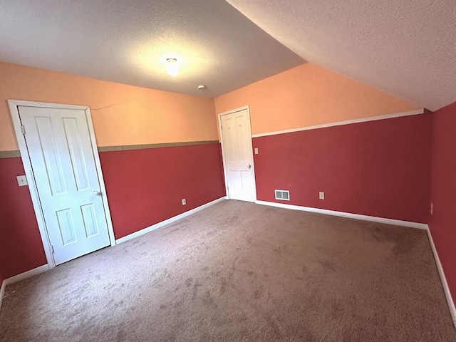 additional living space featuring vaulted ceiling, a textured ceiling, and carpet