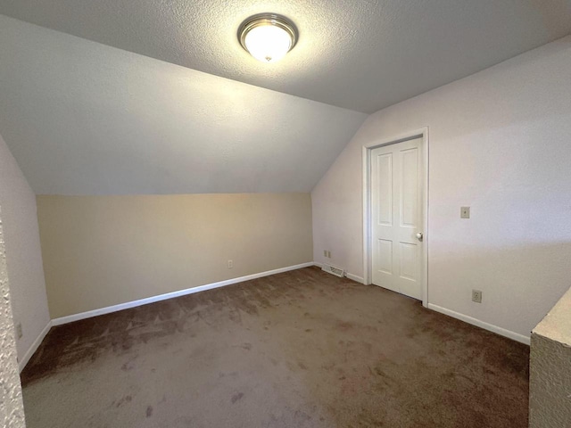 bonus room featuring vaulted ceiling, dark carpet, and a textured ceiling