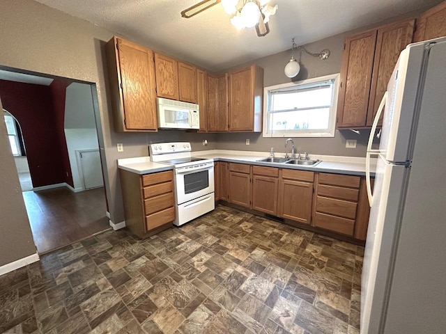 kitchen with sink, a textured ceiling, and white appliances