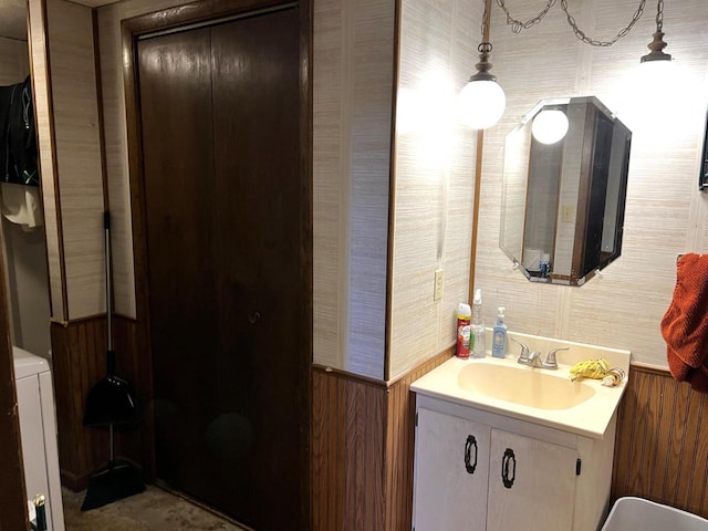 bathroom with washer / clothes dryer, vanity, and wooden walls