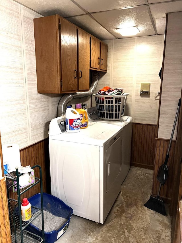 laundry area with washer and clothes dryer, cabinets, and wood walls