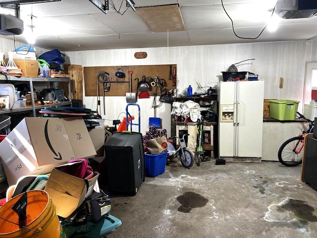 garage with a garage door opener and white fridge with ice dispenser