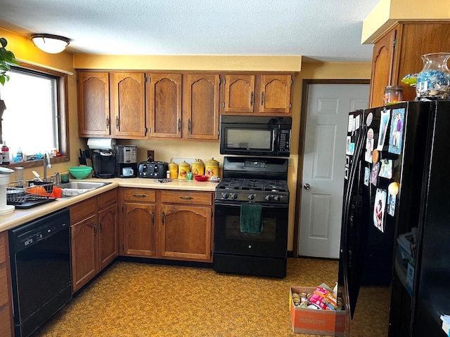 kitchen with sink, a textured ceiling, and black appliances