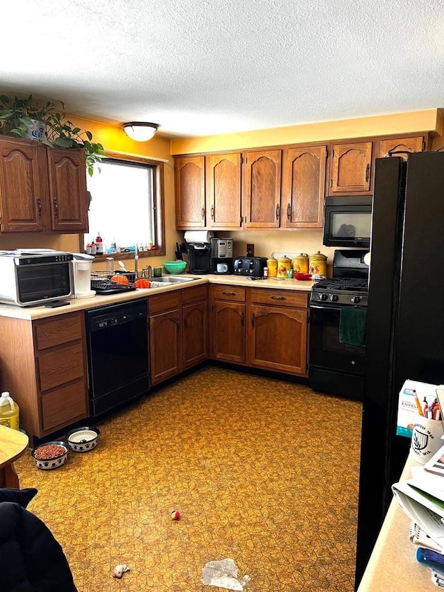 kitchen with sink, black appliances, and a textured ceiling