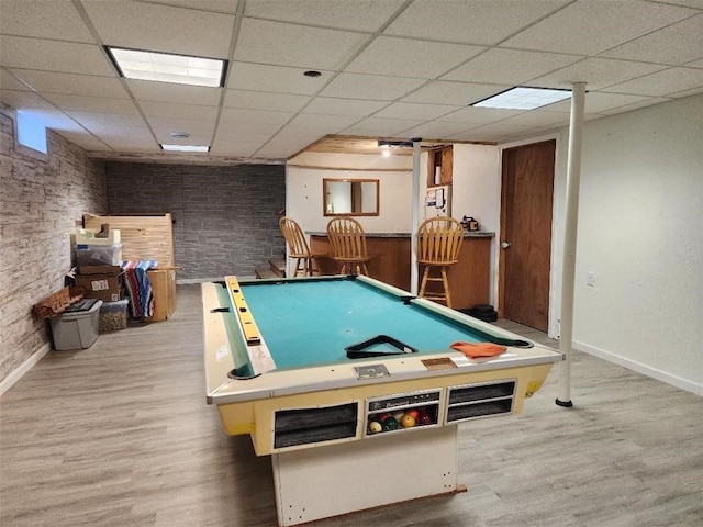 game room featuring a paneled ceiling, wood-type flooring, and bar area