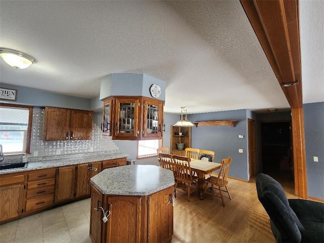 kitchen featuring pendant lighting, sink, decorative backsplash, a center island, and a textured ceiling