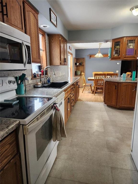 kitchen featuring white electric stove, decorative light fixtures, sink, and backsplash