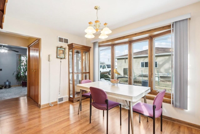 dining room with a healthy amount of sunlight, an inviting chandelier, and light hardwood / wood-style flooring