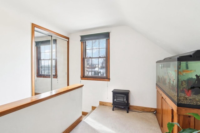 additional living space with vaulted ceiling, light carpet, and a wood stove