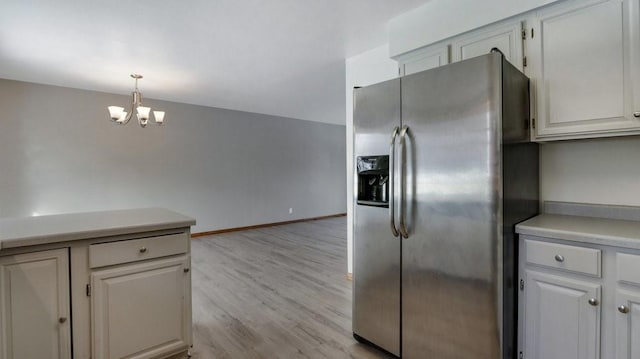 kitchen with pendant lighting, white cabinetry, stainless steel fridge, a notable chandelier, and light hardwood / wood-style floors