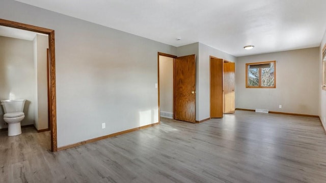 unfurnished bedroom featuring connected bathroom and light hardwood / wood-style flooring