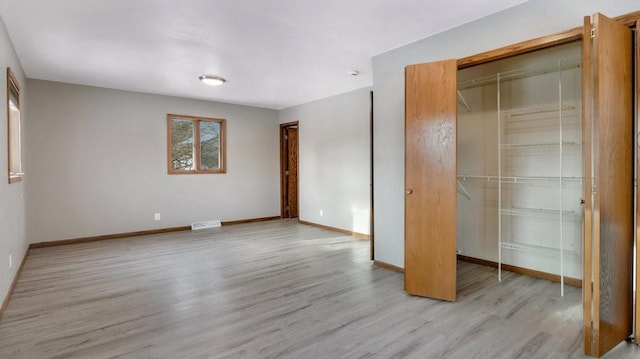 unfurnished bedroom featuring light hardwood / wood-style flooring and a closet