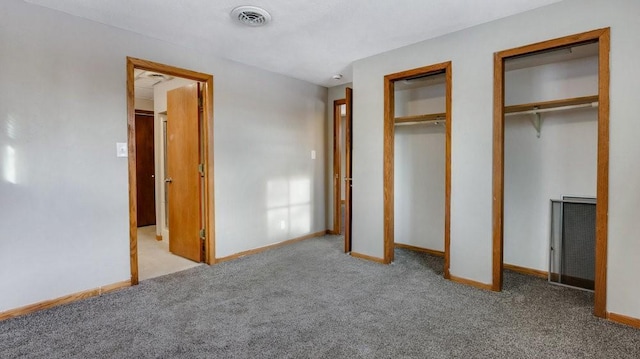 unfurnished bedroom featuring multiple closets and light colored carpet