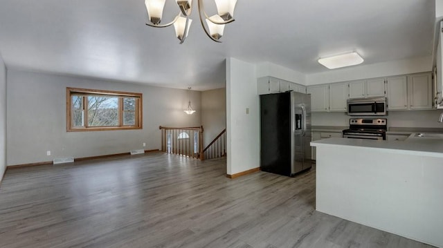 kitchen featuring sink, light hardwood / wood-style flooring, stainless steel appliances, decorative light fixtures, and a chandelier