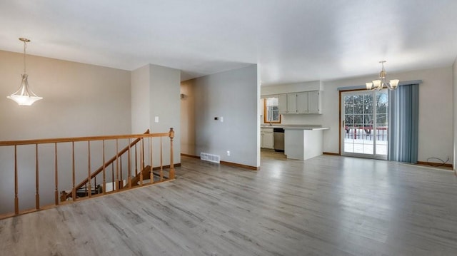 unfurnished room with an inviting chandelier and light wood-type flooring