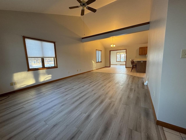 unfurnished living room with ceiling fan with notable chandelier, high vaulted ceiling, and light hardwood / wood-style floors