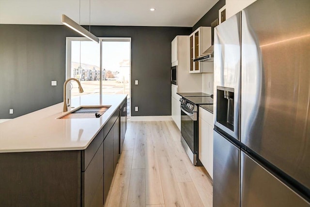 kitchen featuring sink, white cabinetry, a kitchen island, stainless steel appliances, and light hardwood / wood-style floors