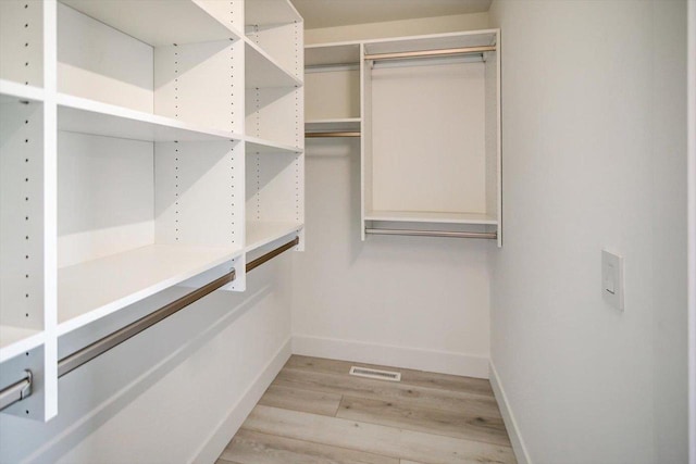 walk in closet with light hardwood / wood-style flooring