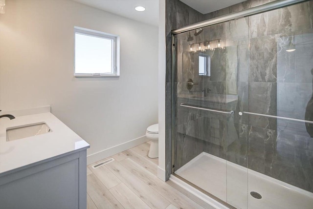 bathroom featuring vanity, hardwood / wood-style flooring, a shower with door, and toilet