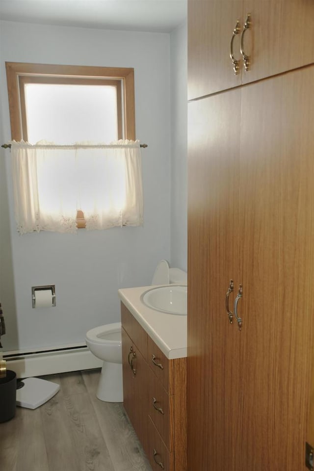 bathroom with vanity, wood-type flooring, toilet, and baseboard heating