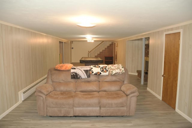 living room featuring a baseboard radiator, ornamental molding, and light wood-type flooring