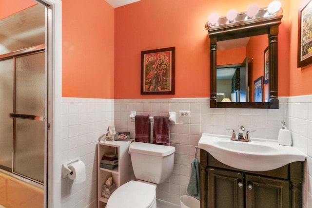 full bathroom featuring vanity, combined bath / shower with glass door, tile walls, and toilet