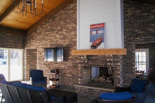 unfurnished living room with brick wall, high vaulted ceiling, and plenty of natural light