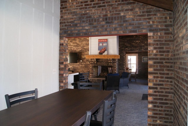 carpeted dining space featuring vaulted ceiling and a brick fireplace