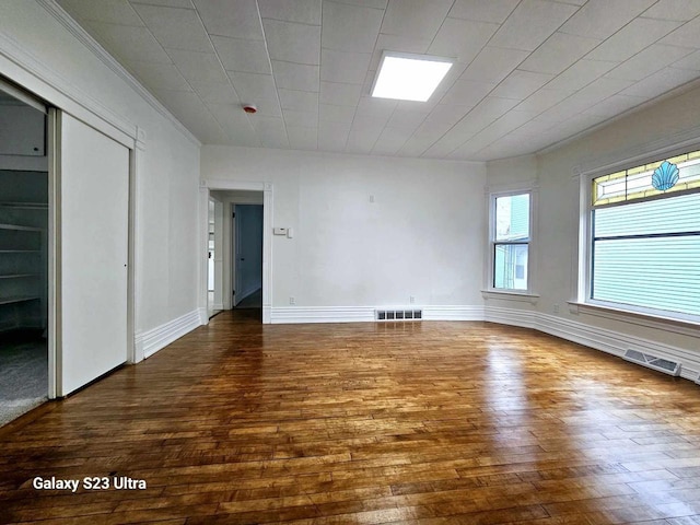 empty room with hardwood / wood-style flooring and crown molding