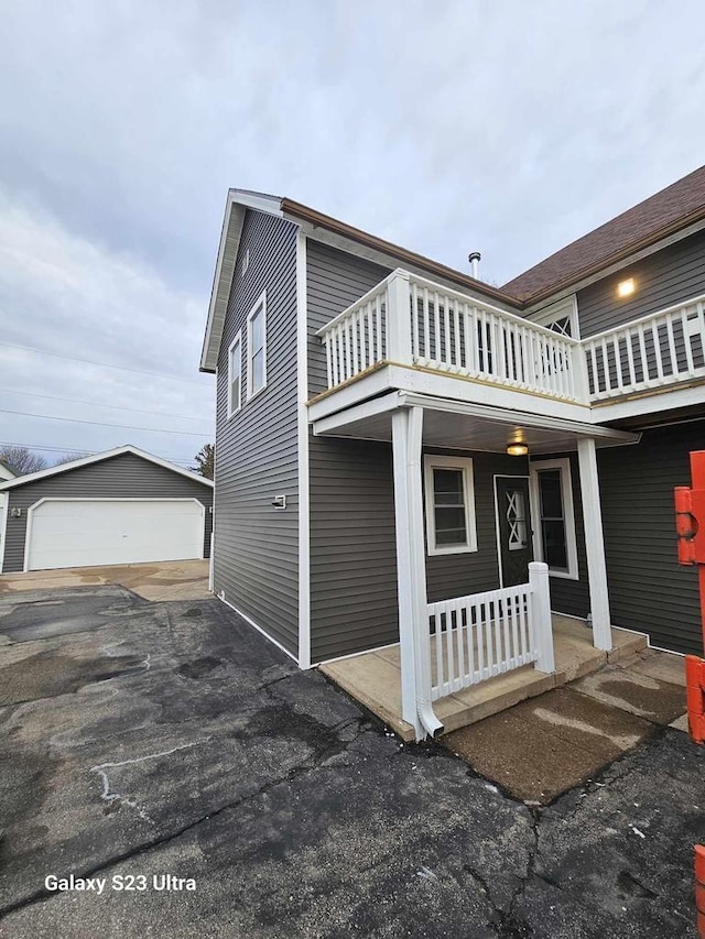 exterior space with a garage, a balcony, and an outbuilding