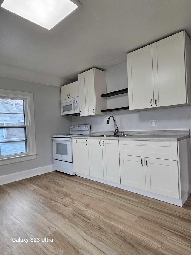 kitchen featuring sink, white appliances, light hardwood / wood-style floors, and white cabinets