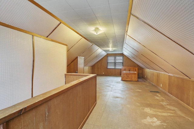 additional living space featuring lofted ceiling and wood walls