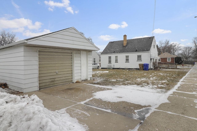 snow covered house featuring a garage and an outdoor structure