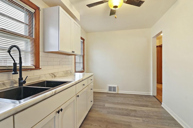 kitchen with white cabinetry, sink, decorative backsplash, ceiling fan, and light hardwood / wood-style floors