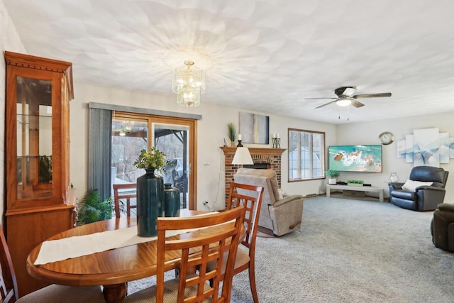 dining space featuring ceiling fan with notable chandelier, a fireplace, and carpet floors