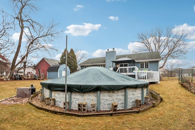 rear view of house featuring a swimming pool side deck, a storage unit, and a lawn