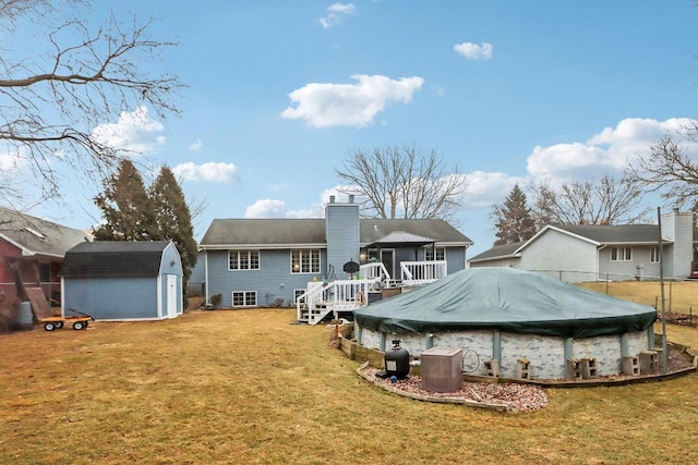 rear view of house featuring a pool side deck, a yard, and a storage unit