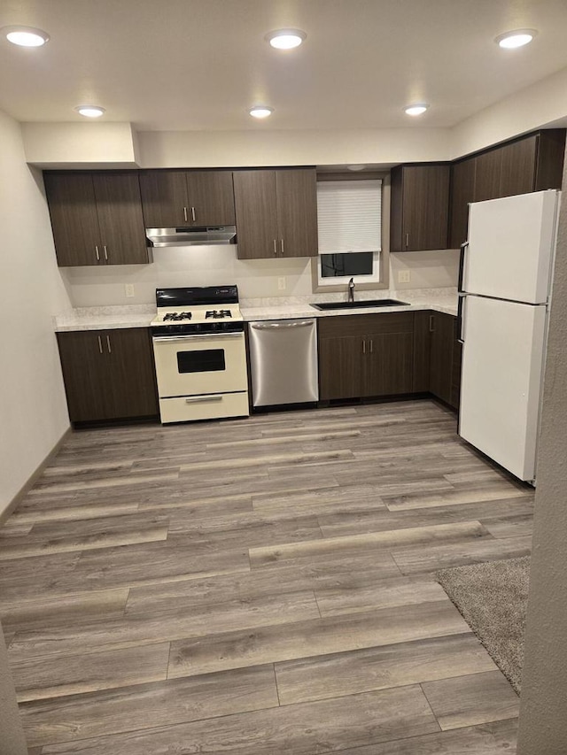 kitchen featuring dark brown cabinetry, white appliances, and light wood-type flooring