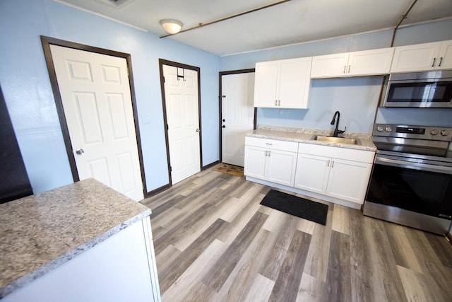 kitchen with stainless steel appliances, sink, light hardwood / wood-style flooring, and white cabinets