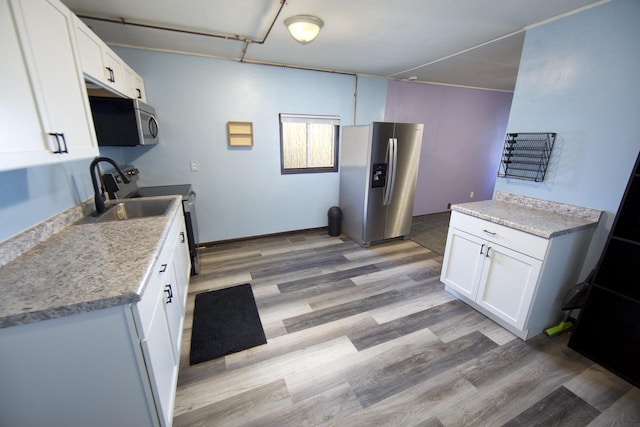 kitchen with white cabinetry, appliances with stainless steel finishes, sink, and light wood-type flooring